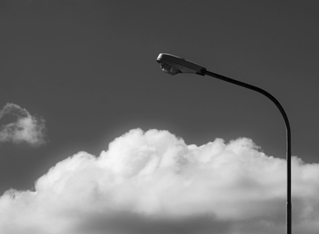 Black and white photo of a streetlight against cumulus clouds